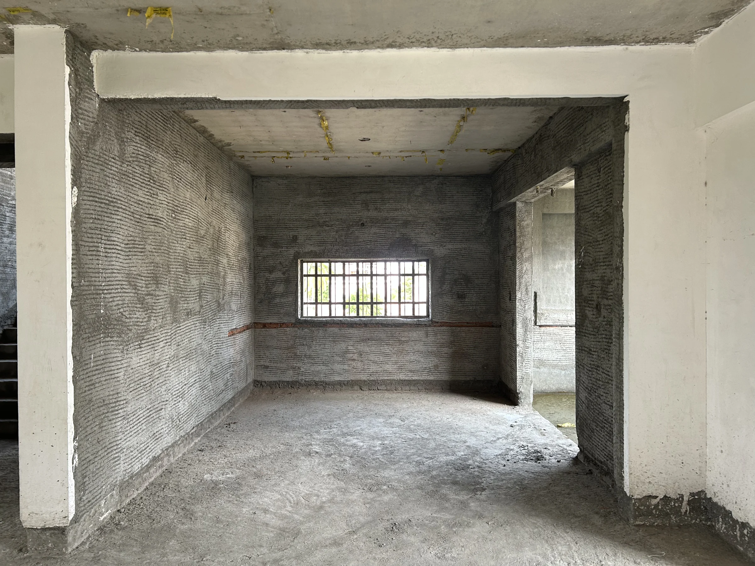 Site photograph: a bare concrete and block-work hall with one window